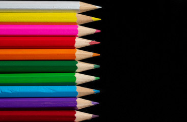 Coloured pencils isolated on black background close up. Vintage look Macro photography. Pencils Wallpaper. Bundle of rainbow colored pencils with selected focus on tips. Multicolored rainbow pencils.