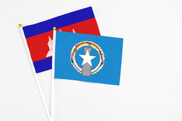 Northern Mariana Islands and Cambodia stick flags on white background. High quality fabric, miniature national flag. Peaceful global concept.White floor for copy space.