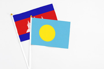 Palau and Cambodia stick flags on white background. High quality fabric, miniature national flag. Peaceful global concept.White floor for copy space.