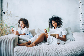 Relaxing woman with book and girl with phone