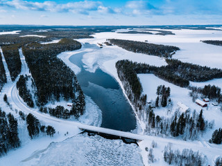 Aerial top view of bridge road above frozen river in snow winter Finland.