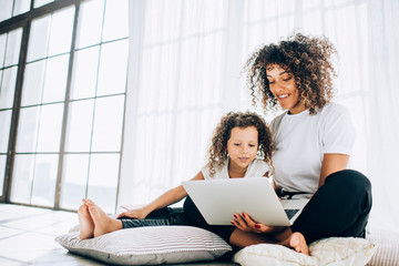 Cute little girl with mother using laptop