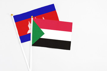 Sudan and Cambodia stick flags on white background. High quality fabric, miniature national flag. Peaceful global concept.White floor for copy space.