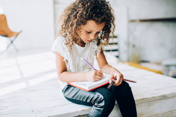 Adorable little girl writing in notepad
