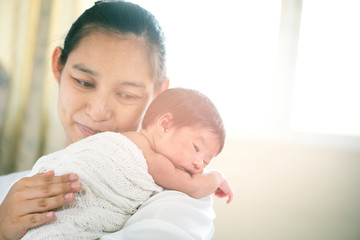 New born infant on white cloth and carrying by her mother while laying on her shoulder. Mother Love Concept 
