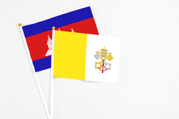 Vatican City and Cambodia stick flags on white background. High quality fabric, miniature national flag. Peaceful global concept.White floor for copy space.