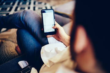 Back view of male checking banking balance on mobile phone connected to home internet, millennial...