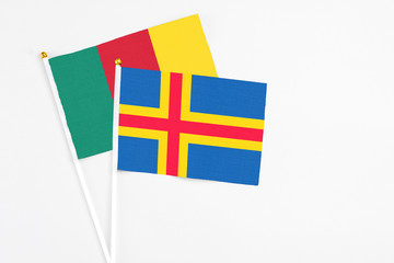 Aland Islands and Cameroon stick flags on white background. High quality fabric, miniature national flag. Peaceful global concept.White floor for copy space.