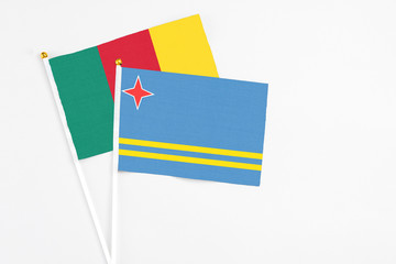 Aruba and Cameroon stick flags on white background. High quality fabric, miniature national flag. Peaceful global concept.White floor for copy space.