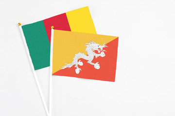 Bhutan and Cameroon stick flags on white background. High quality fabric, miniature national flag. Peaceful global concept.White floor for copy space.