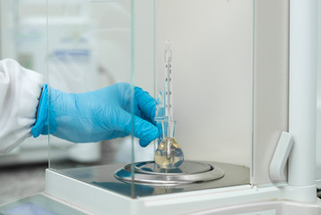 Analyst is weighing the pycnometer contain liquid sample for the test of density, concept of method...