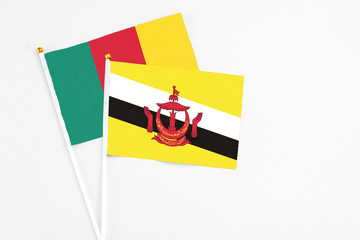 Brunei and Cameroon stick flags on white background. High quality fabric, miniature national flag. Peaceful global concept.White floor for copy space.
