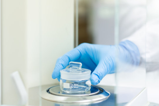 The operator is weighing the empty weighing bottle on the analytical balance for glassware calibration work, concept of qc laboratory in pharmaceutical industry.