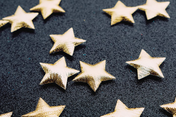 Golden stars on sparkly shining black festive background.