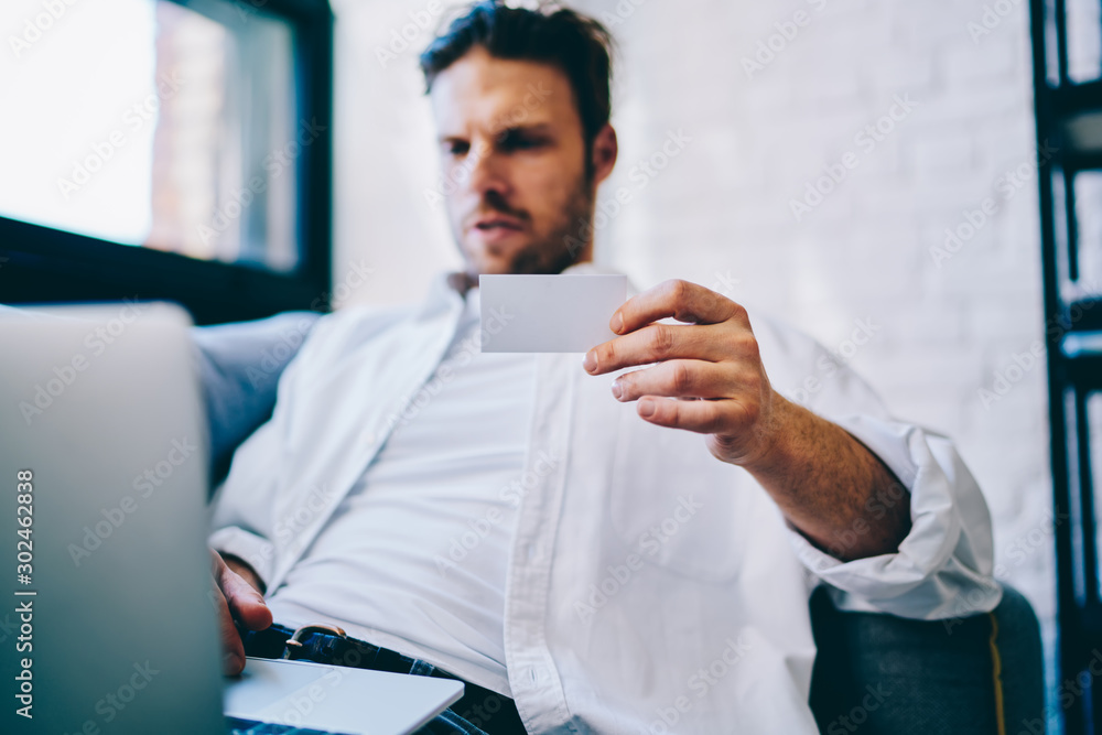 Aufkleber selective focus on male hand holding paper business card and typing information on laptop computer c