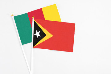 East Timor and Cameroon stick flags on white background. High quality fabric, miniature national flag. Peaceful global concept.White floor for copy space.