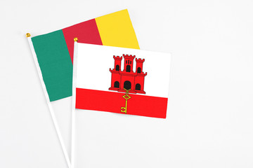 Gibraltar and Cameroon stick flags on white background. High quality fabric, miniature national flag. Peaceful global concept.White floor for copy space.