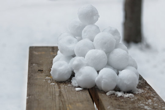 A slide of stuck snowballs on a wooden bench in the yard.
