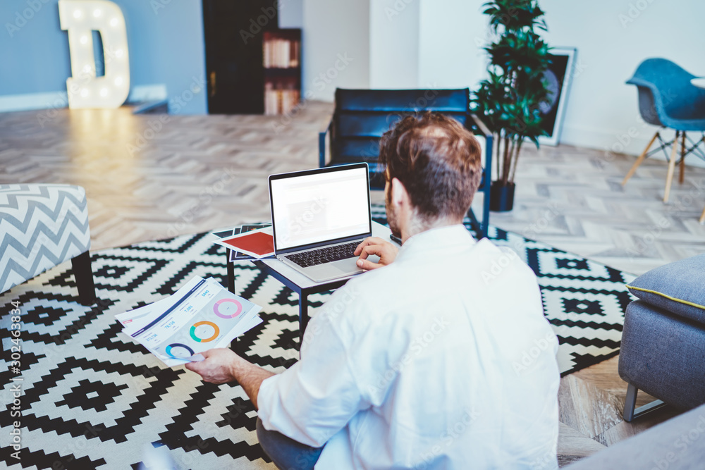 Aufkleber back view of man sitting on floor with laptop device with copy space area for your internet content,