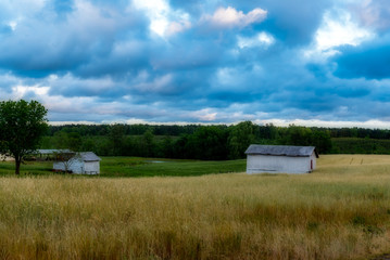 White barn in a field with sky and clouds in the background
