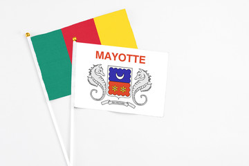 Mayotte and Cameroon stick flags on white background. High quality fabric, miniature national flag. Peaceful global concept.White floor for copy space.