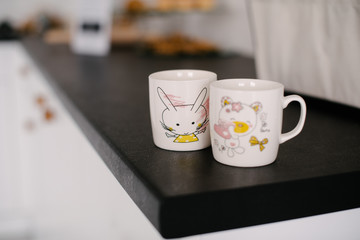 2 tea cups on a black kitchen shelf