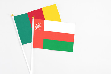 Oman and Cameroon stick flags on white background. High quality fabric, miniature national flag. Peaceful global concept.White floor for copy space.