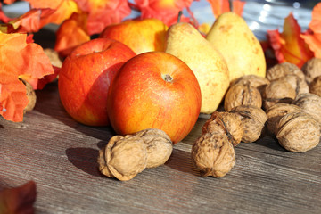 Äpfel, Birnen und Walnüsse auf einem rustikalen Holztisch als herbstliches Motiv