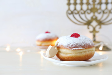 religion image of jewish holiday Hanukkah background with spinning top and doughnut over white background