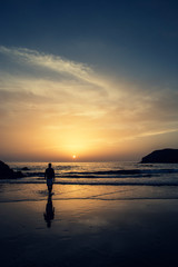 Hombre andando por la playa al atardecer