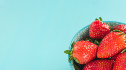 bright printed bowl of fresh strawberries on blue wooden background