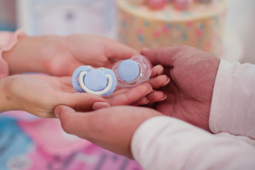 Blue pacifier in the hands. Family waiting for little boy