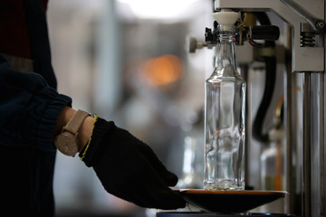 Glassworks. Hands hold a glass bottle over the device. Quality control of glass containers