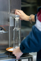 Glassworks. Hands hold a glass bottle over the device. Quality control of glass containers