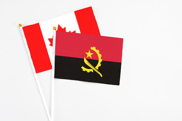 Angola and Canada stick flags on white background. High quality fabric, miniature national flag....