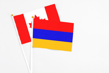 Armenia and Canada stick flags on white background. High quality fabric, miniature national flag. Peaceful global concept.White floor for copy space.