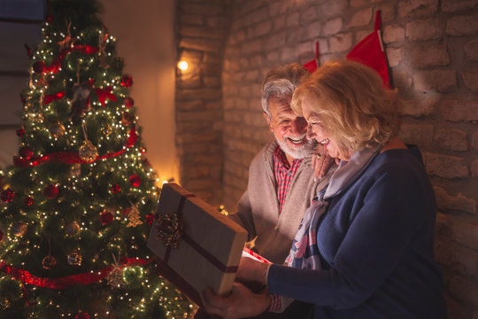 Senior couple opening glowing gift box on Christmas Eve