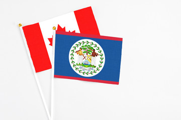 Belize and Canada stick flags on white background. High quality fabric, miniature national flag. Peaceful global concept.White floor for copy space.