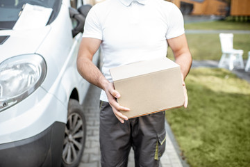 Delivery man holding carboard parcel outdoors, close-up on the box with blank space