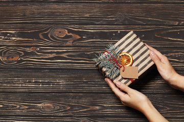 Craft decorative gift in a female hand on a wooden background. Place for the test. Top View.