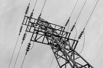 Rusty power line is on the blue sky background. Black and white photo
