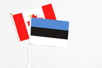 Estonia and Canada stick flags on white background. High quality fabric, miniature national flag. Peaceful global concept.White floor for copy space.