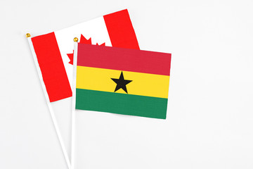 Ghana and Canada stick flags on white background. High quality fabric, miniature national flag. Peaceful global concept.White floor for copy space.