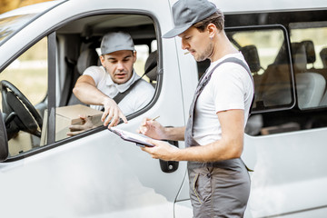 Delivery company employees in uniform delivering goods by cargo van vehicle, mover with a car...