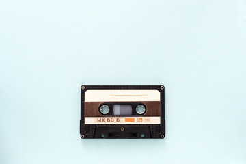 Audio tape cassette on a light blue background close-up. Top view