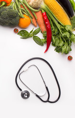 Stethoscope and collection of fresh vegetables on white