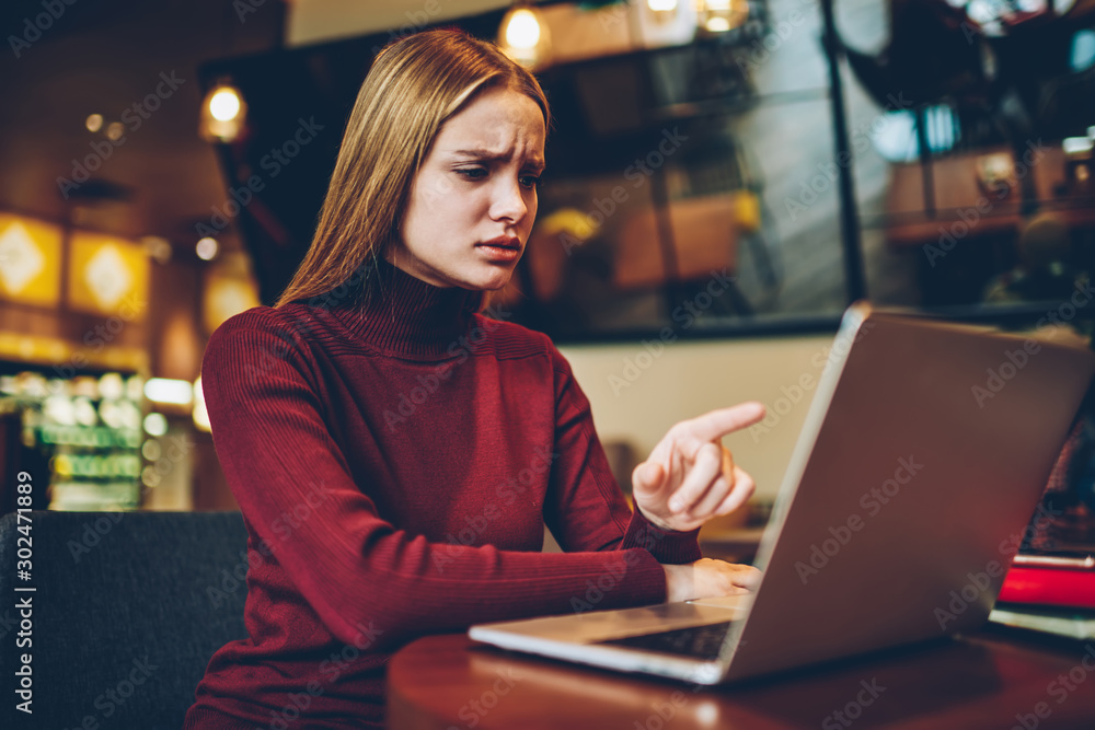 Poster thoughtful woman puzzled on received email from work pointing on laptop screen while spending time i