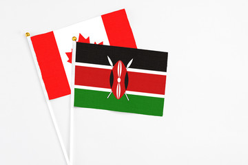 Kenya and Canada stick flags on white background. High quality fabric, miniature national flag. Peaceful global concept.White floor for copy space.