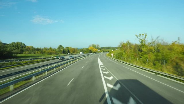Bus driver point of view. Driving on straight road passing by highway entrance in sunny day.