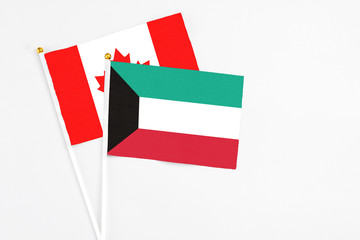 Kuwait and Canada stick flags on white background. High quality fabric, miniature national flag. Peaceful global concept.White floor for copy space.